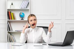 A virtual receptionist with a headset at her desk, representing virtual receptionist cost.